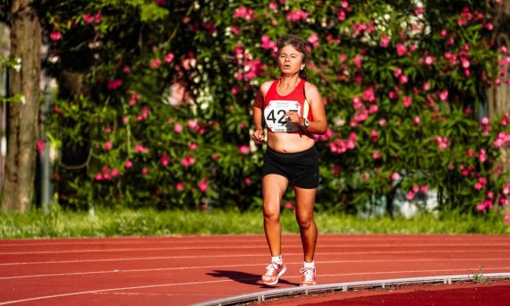Middle aged female athlete in sportswear running during track and field competition while looking forward
